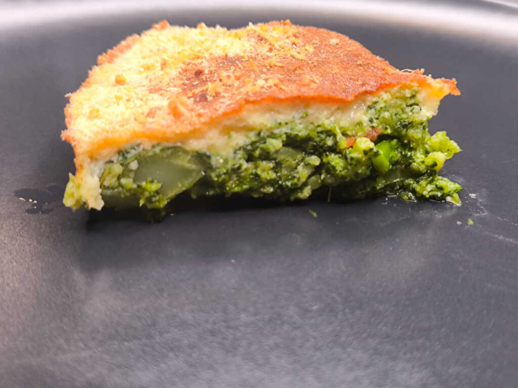 torta rustica con broccoli e uova e mozzarella su un piatto nero