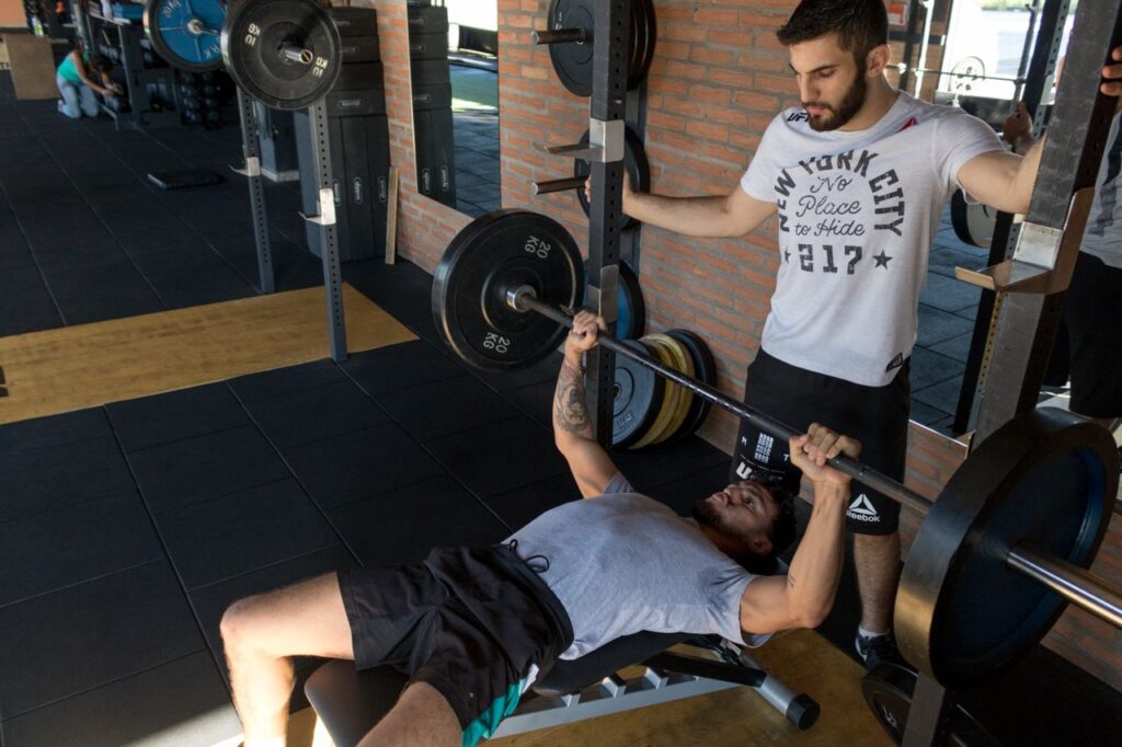 uomo che fa panca piana con supporto di uno spotter